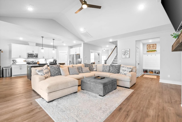 living room featuring ceiling fan, high vaulted ceiling, sink, and light wood-type flooring