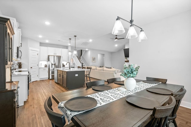 dining space with sink, vaulted ceiling, ceiling fan, and light wood-type flooring