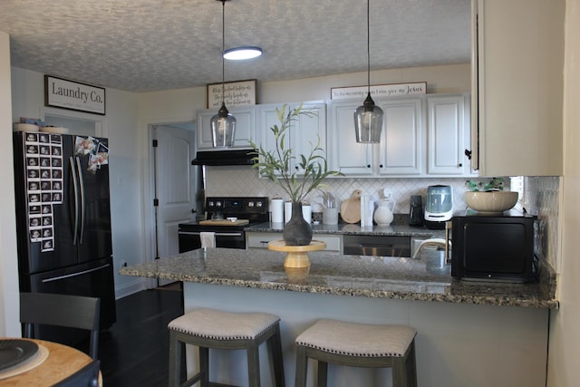 kitchen featuring decorative backsplash, dark stone countertops, hanging light fixtures, and black appliances