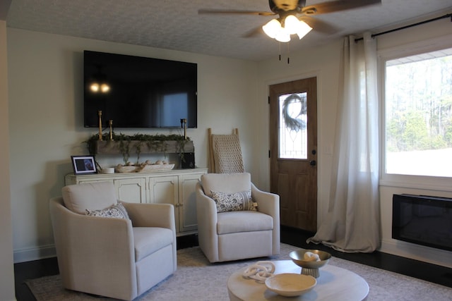 living room featuring ceiling fan and a textured ceiling