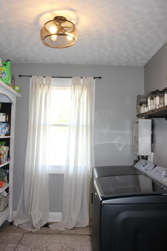 laundry area featuring water heater, a textured ceiling, and independent washer and dryer