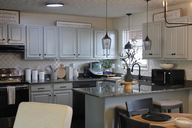 kitchen featuring ventilation hood, dark stone countertops, a kitchen breakfast bar, stainless steel range with electric stovetop, and hanging light fixtures