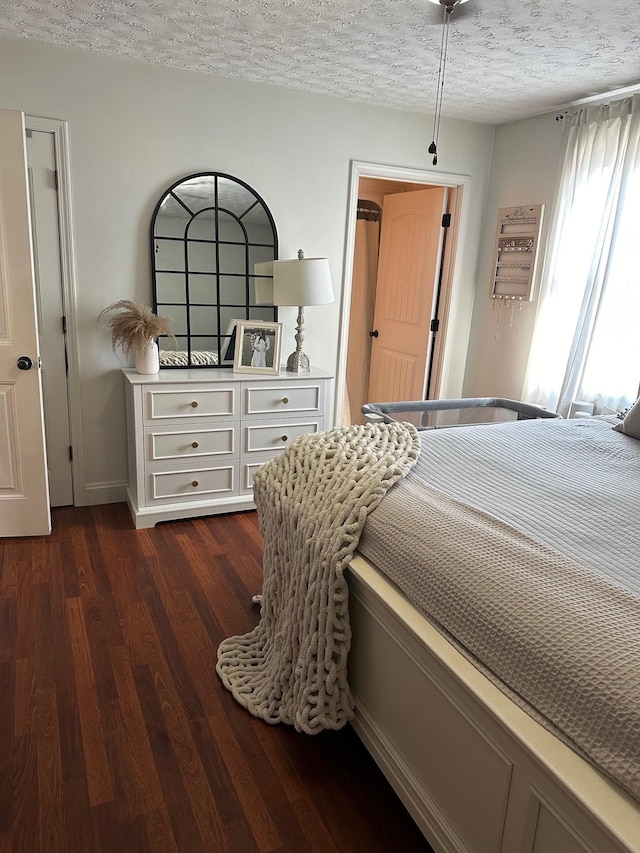 bedroom with dark hardwood / wood-style floors and a textured ceiling