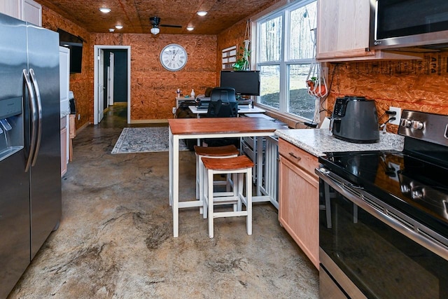 kitchen featuring appliances with stainless steel finishes, a breakfast bar, and light brown cabinets