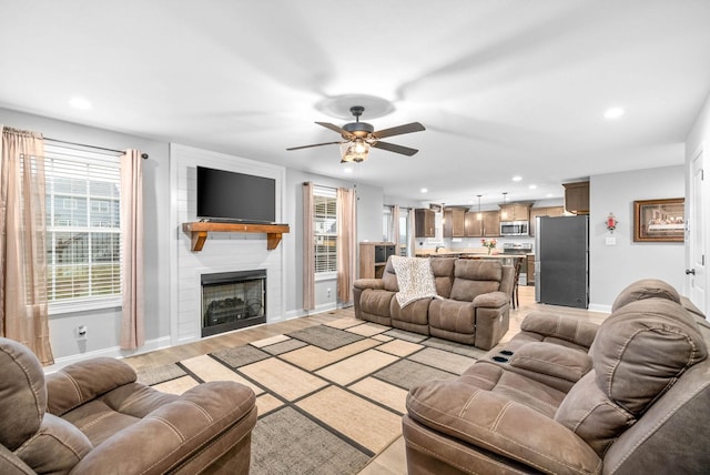 living room featuring light hardwood / wood-style floors, a large fireplace, and ceiling fan