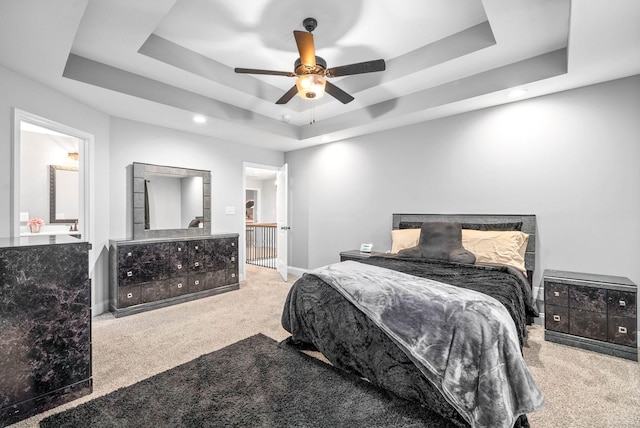 carpeted bedroom featuring ceiling fan and a tray ceiling