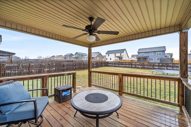 wooden deck with a trampoline, a yard, and ceiling fan