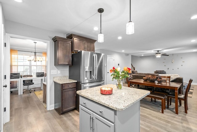 kitchen featuring a kitchen island, stainless steel fridge with ice dispenser, pendant lighting, light stone counters, and light hardwood / wood-style floors