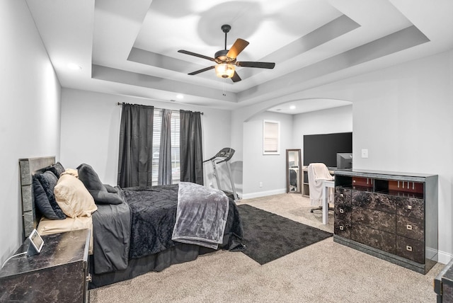 carpeted bedroom featuring ceiling fan and a tray ceiling