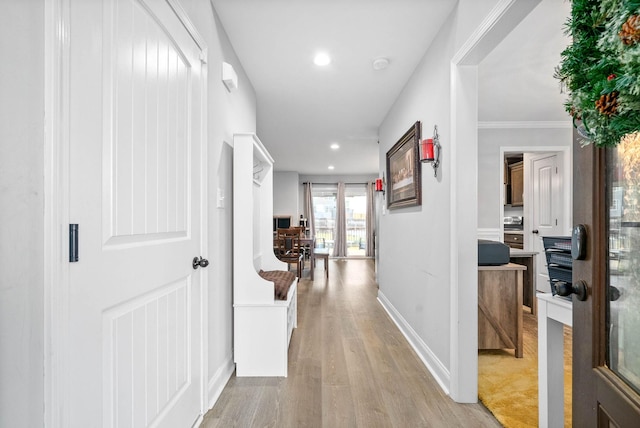 hall with ornamental molding and light hardwood / wood-style flooring