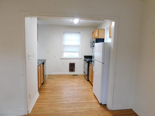 kitchen with light brown cabinets, appliances with stainless steel finishes, heating unit, and light hardwood / wood-style floors