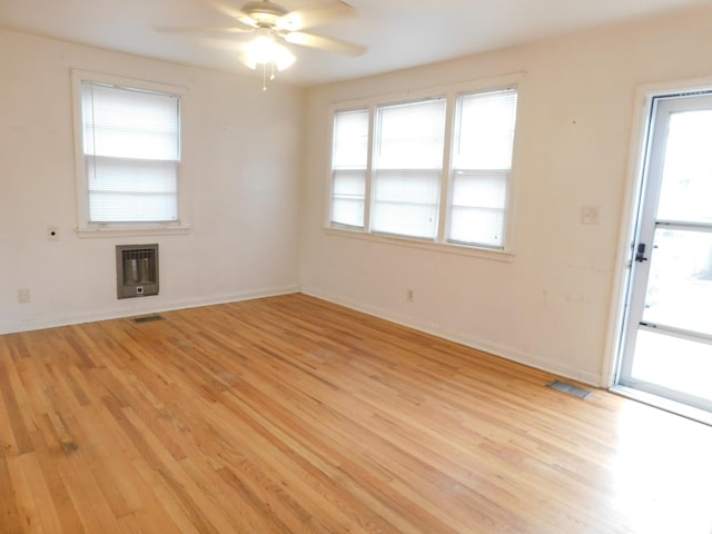 empty room featuring heating unit, ceiling fan, and light hardwood / wood-style flooring