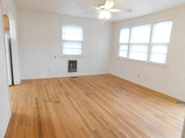 spare room featuring heating unit, light hardwood / wood-style flooring, and ceiling fan