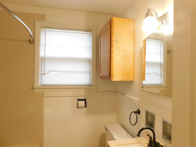 bathroom with walk in shower, sink, and toilet