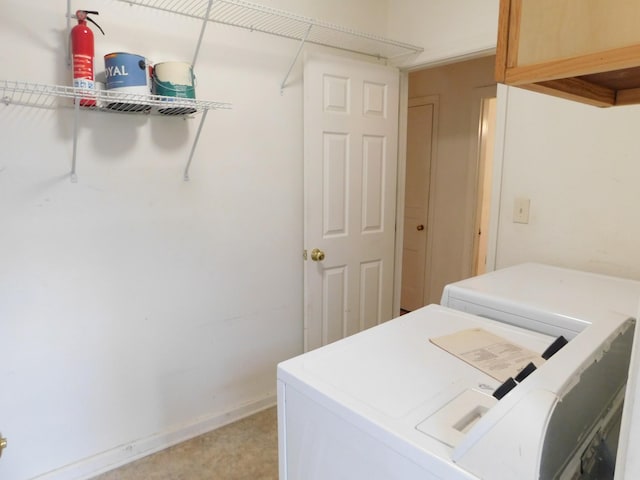 clothes washing area featuring washer and clothes dryer and cabinets