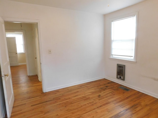 unfurnished room featuring heating unit and light wood-type flooring