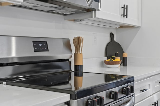 kitchen featuring white cabinetry, light stone countertops, and stainless steel electric range