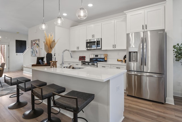 kitchen featuring sink, hanging light fixtures, a center island with sink, appliances with stainless steel finishes, and white cabinets