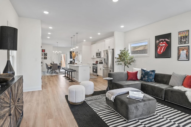 living room featuring light wood-type flooring, a notable chandelier, baseboards, and recessed lighting