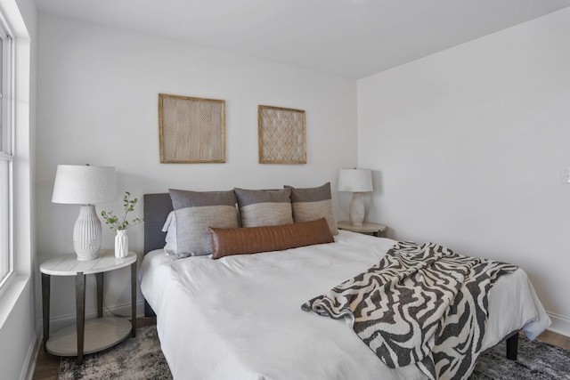 bedroom with multiple windows, baseboards, and wood finished floors