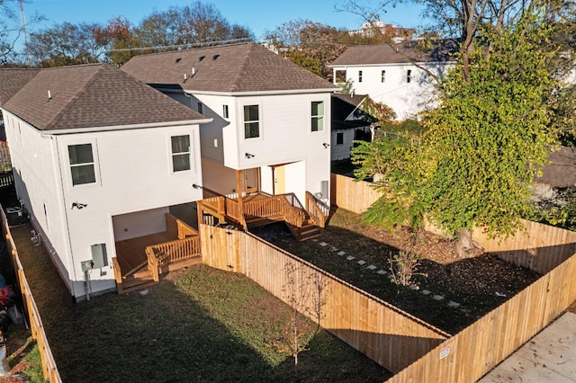 rear view of house featuring a fenced backyard, a deck, and roof with shingles