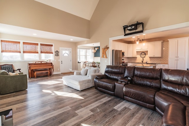 living room with an inviting chandelier, high vaulted ceiling, and hardwood / wood-style floors