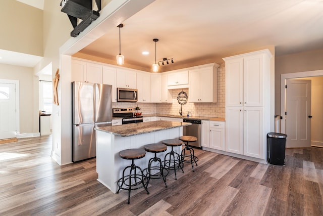 kitchen featuring a breakfast bar, appliances with stainless steel finishes, a center island, white cabinets, and dark stone counters