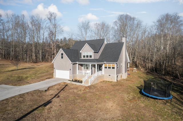 front of property with a porch, a garage, a front lawn, and a trampoline