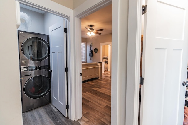 laundry area with dark wood-type flooring, stacked washer and clothes dryer, and ceiling fan