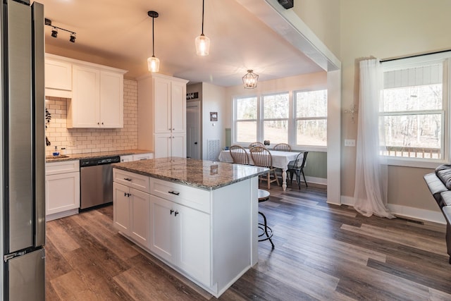 kitchen featuring white cabinetry, stainless steel appliances, a kitchen breakfast bar, and stone counters