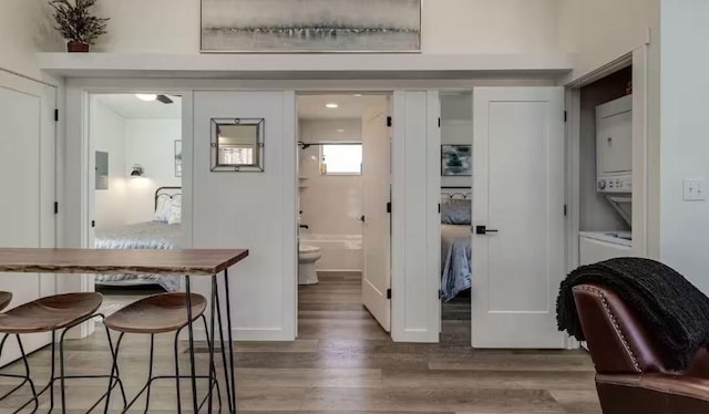 interior space with stacked washer and dryer, hardwood / wood-style flooring, electric panel, and toilet