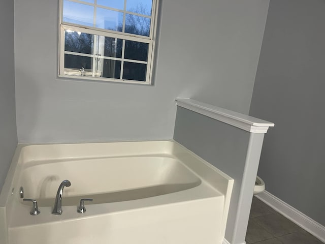 bathroom featuring a tub to relax in, tile patterned floors, and toilet