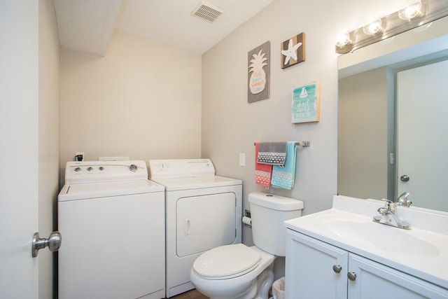 bathroom with vanity, washing machine and dryer, and toilet