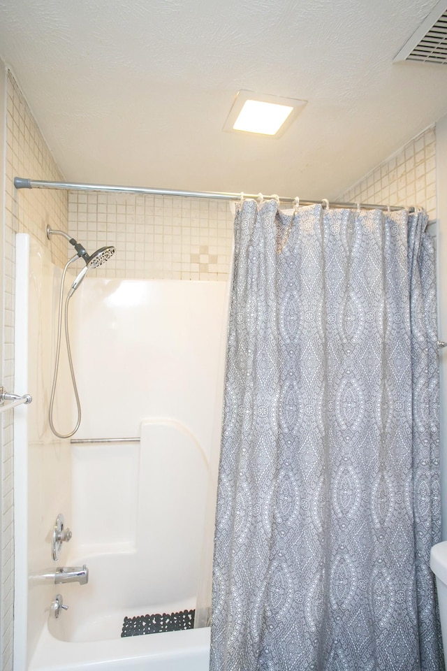 bathroom featuring shower / bath combo and a textured ceiling