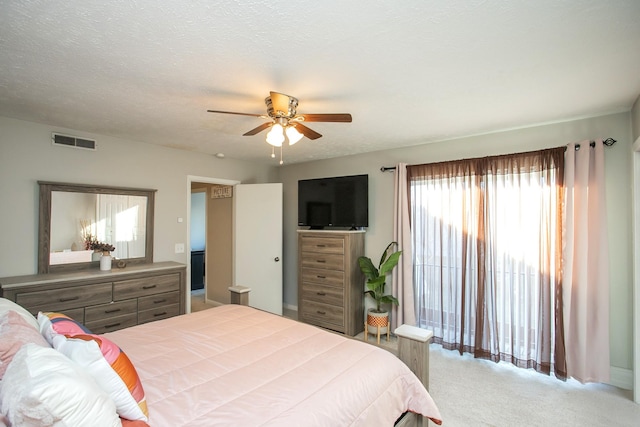 carpeted bedroom featuring ceiling fan and a textured ceiling