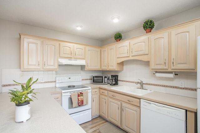 kitchen with light brown cabinetry, sink, decorative backsplash, white appliances, and light hardwood / wood-style flooring