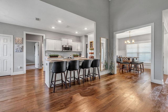 kitchen with white cabinetry, dark hardwood / wood-style floors, a notable chandelier, and a kitchen breakfast bar