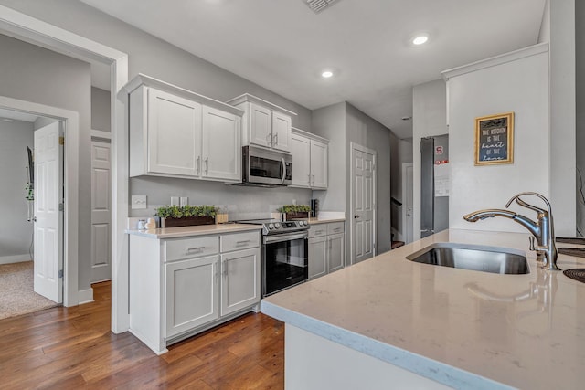 kitchen with light stone countertops, white cabinetry, appliances with stainless steel finishes, and sink