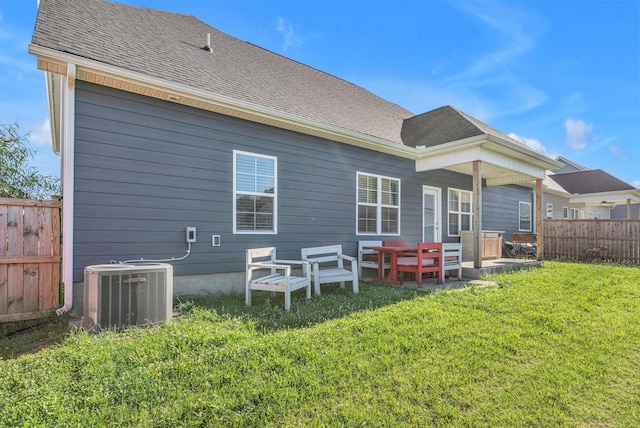 back of property with central AC unit and a lawn