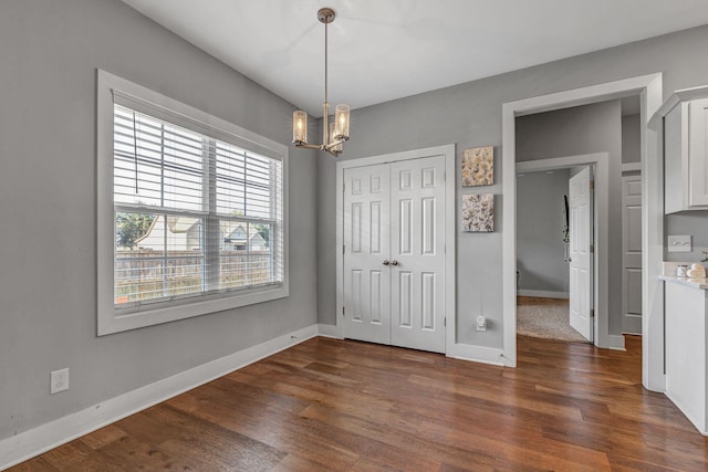 interior space with dark wood-type flooring, a notable chandelier, and a closet