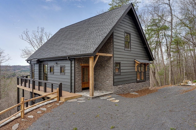 chalet / cabin featuring stone siding and a shingled roof