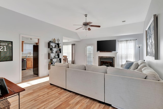 living room featuring ceiling fan, lofted ceiling, sink, and light hardwood / wood-style floors