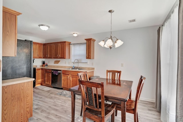 kitchen featuring sink, stainless steel dishwasher, light hardwood / wood-style floors, and decorative light fixtures