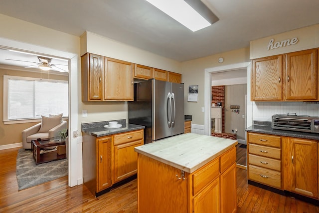 kitchen featuring stainless steel refrigerator, ceiling fan, dark hardwood / wood-style floors, and a center island