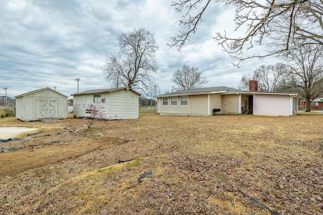 rear view of property with a yard and a storage unit