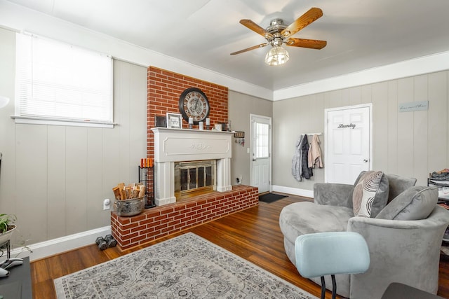 living room featuring ceiling fan, dark hardwood / wood-style floors, and a brick fireplace