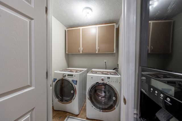 laundry area featuring light tile patterned floors, washing machine and dryer, cabinets, and a textured ceiling