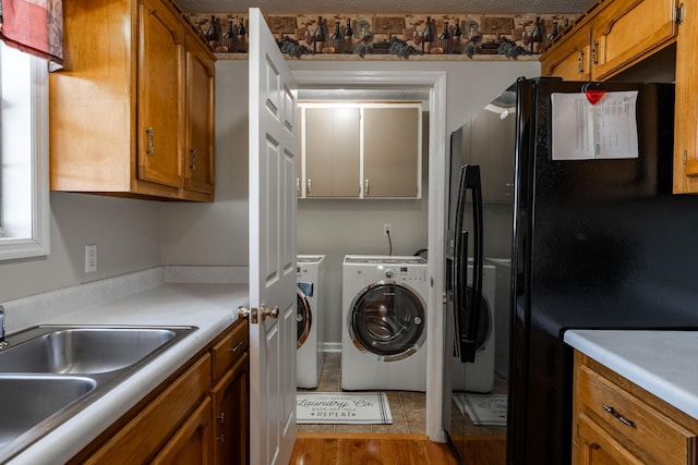 washroom featuring cabinets, independent washer and dryer, sink, and light hardwood / wood-style flooring