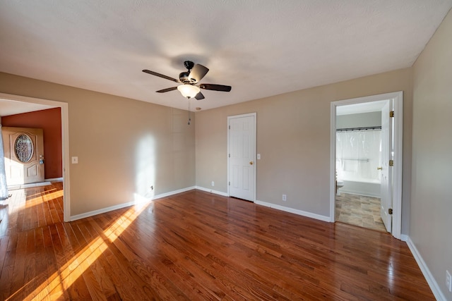 unfurnished bedroom featuring ceiling fan, ensuite bath, and dark hardwood / wood-style floors