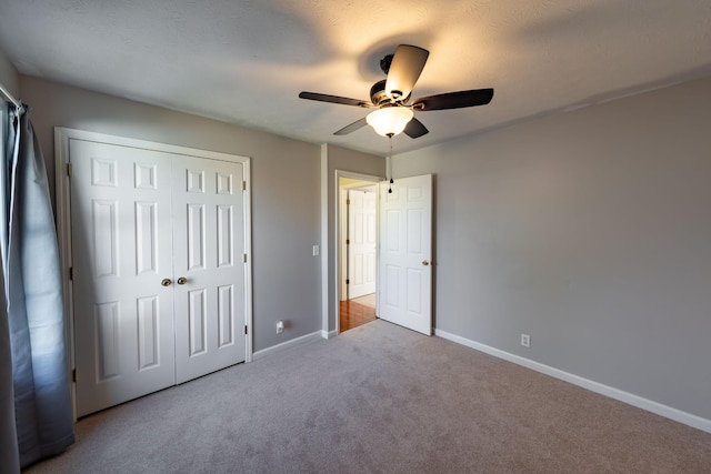 unfurnished bedroom with light colored carpet, a closet, and ceiling fan